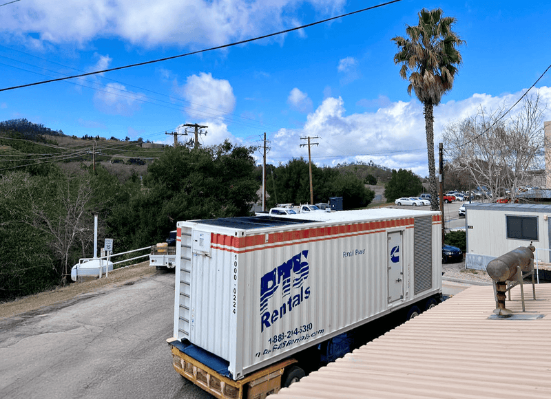 A PTS Rentals containerised rental power unit on a trailer at a job site